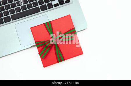 Confezione regalo rossa e computer portatile isolato su sfondo bianco, spazio per le copie Foto Stock