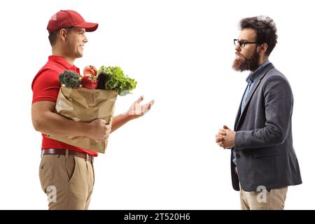 Immagine del profilo di un corriere con una borsa della spesa che parla con un cliente maschio barbuto isolato su sfondo bianco Foto Stock