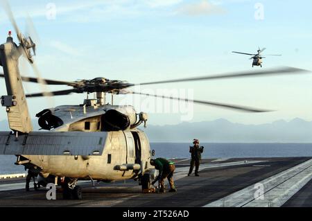 0807015961C-004 SULU SEA (1 luglio 2008) un SH-60F Seahawk vola in lontananza mentre l'equipaggio e gli equipaggi di manutenzione assegnati all'Helicopter Anti-Submarine Squadron (HS) 4 preparano un secondo elicottero per il lancio dalla portaerei USS Ronald Reagan (CVN 76) durante le operazioni umanitarie sull'isola Panay, Filippine. La regione è stata duramente colpita dal tifone Fengshen e i ТBlack KnightsУ hanno volato sette giorni consecutivi per consegnare rifornimenti in località remote dell'isola. Marina degli Stati Uniti Foto Stock