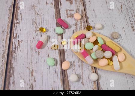 Pillole, compresse e capsule di medicina farmaceutica assortite su cucchiaio di legno. Foto Stock