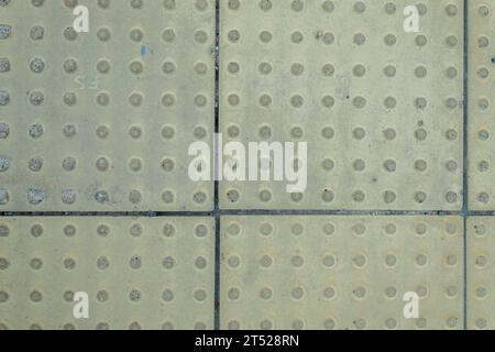 Texture di sfondo di piastrelle gialle per non vedenti e non vedenti. Pavimentazione in Braille tattile in pietra Foto Stock