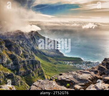 Vista aerea delle nuvole che si infrangono sulla montagna Table a Cape Town, in Sudafrica, con il copyspace. Splendido paesaggio di cespugli verdi e terreni rocciosi Foto Stock