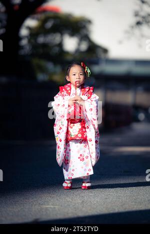 Una bambina che cammina per strada con un kimono giapponese rosso. Foto Stock