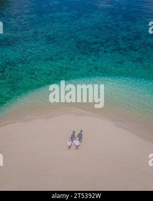 Un paio di uomini e donne in un banco di sabbia bianco nell'oceano dell'isola di Koh Lipe nella Thailandia meridionale in una giornata di sole Foto Stock