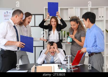 Uomo d'affari maturo che soffre di colleghi rumorosi in ufficio Foto Stock