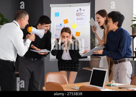 Giovane donna d'affari che soffre di colleghi rumorosi in ufficio Foto Stock