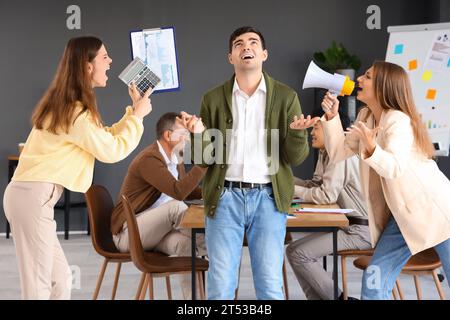 Giovane uomo d'affari che soffre di colleghi rumorosi in ufficio Foto Stock