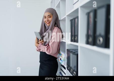 Impiegata musulmana in cerca di documenti in ufficio. Foto Stock