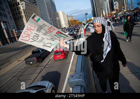 Detroit, Michigan, USA. 28 ottobre 2023. Una donna con un cartello che distrugge l'assedio a Gaza la manda al passaggio del traffico durante una manifestazione di "cessate il fuoco a Gaza". Il raduno ha visto una massiccia affluenza di oltre un migliaio di manifestanti provenienti da Detroit. I residenti di Detroit e delle comunità circostanti hanno tenuto frequenti raduni mentre Israele continua a intensificare i bombardamenti e gli attacchi a Gaza a seguito di un attacco di Hamas su Israele il 7 ottobre 2023. Detroit ospita la più grande popolazione di arabi negli Stati Uniti, compresi molti palestinesi. (Immagine di credito: © Matthew Hatcher/SOPA Images via Foto Stock