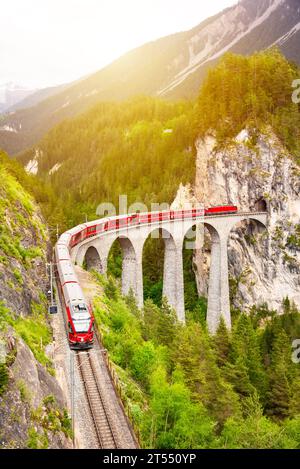Treno rosso svizzero sul viadotto in montagna per un giro panoramico Foto Stock