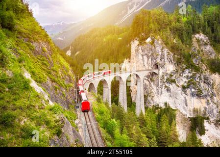Treno rosso svizzero sul viadotto in montagna per un giro panoramico Foto Stock