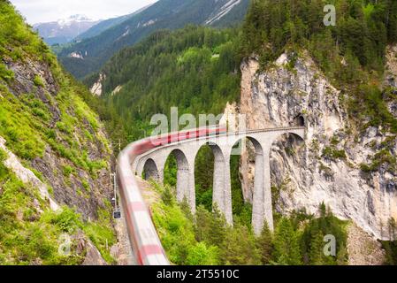 Treno rosso svizzero sul viadotto in montagna per un giro panoramico Foto Stock