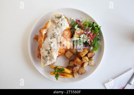 Panino brioche con brioche di uova strapazzate con pesche, feta con foglie di rucola e patate saltate. Foto Stock