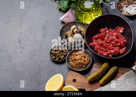 Cottura di una saporita tartare di manzo con cetriolini sottaceto e pane tostato. Con spazio di copia Foto Stock