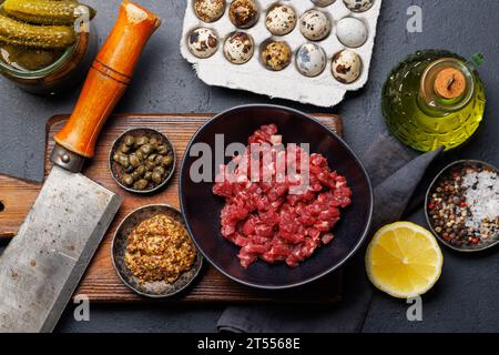 Cottura di una saporita tartare di manzo con cetriolini sottaceto e pane tostato. Spianatura piatta Foto Stock