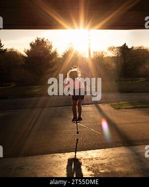 Ragazza che salta sul giocattolo primaverile sul marciapiede Foto Stock