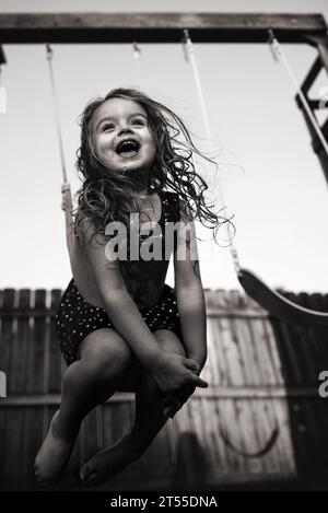 Bella bambina felice che dondola nel cortile posteriore Foto Stock