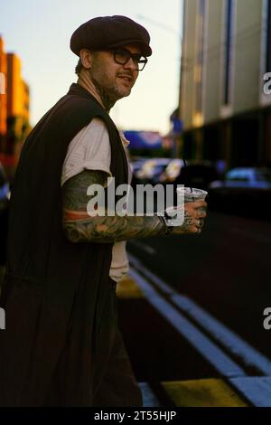 Bell'uomo in città beve caffè, tatuato. Foto Stock
