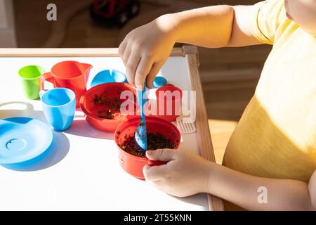 Il bambino gioca con piatti di plastica e spezie Foto Stock