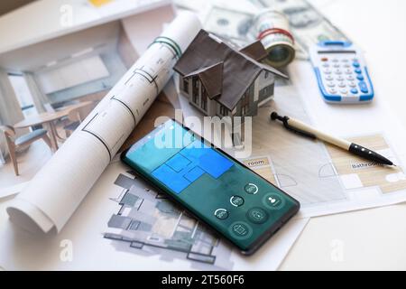 Alcune banconote in euro, una calcolatrice e una chiave di casa in cima ai piani di costruzione. Foto Stock