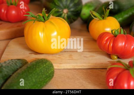 Pomodori grandi maturi, melanzane, verdure su un locale di lavoro in legno della cucina. Molte verdure crude di fondo. Pomodoro, cetrioli. Fornello a casa che fa una h Foto Stock