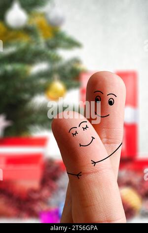 Volti di dita che si abbracciano l'un l'altro isolati su sfondo decorato a Natale. Famiglia felice che festeggia il giorno di Natale Foto Stock