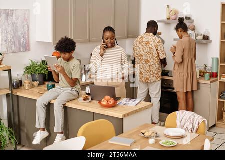 Famiglia nera che passa il tempo a cucinare a casa, lavorare e studiare Foto Stock