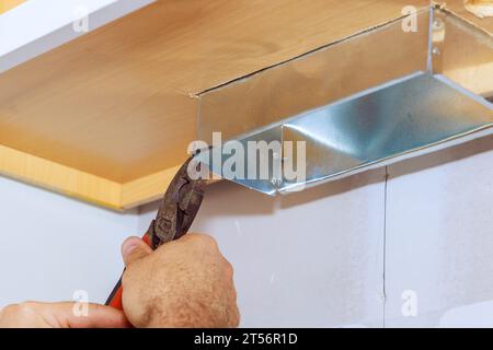 Mentre il lavoratore sta installando cappa da cucina, lo posiziona nell'armadio da cucina Foto Stock