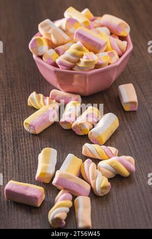 Dolci marshmallow colorati in ciotola sul tavolo di legno. Foto Stock