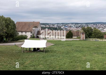 I visitatori fanno un picnic sotto le tende sul glacis o sul prato principale della cittadella a Besancon, con il cancello principale sullo sfondo, a Besancon, in Francia Foto Stock