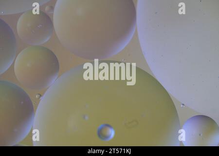 Vista dall'alto le bolle d'olio cadono sull'acqua con sfondo colorato, concetto di fotografia macro Foto Stock