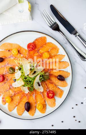 Pesce rosso crudo a fette, con pangrattato bianco, erbe e pomodori ciliegini. Vista dall'alto Foto Stock