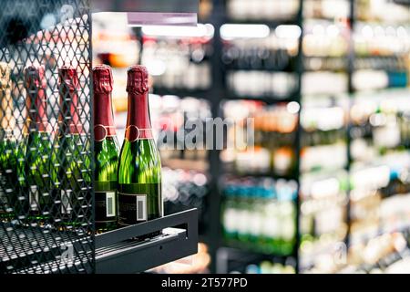 Vino frizzante sullo scaffale del negozio di alcolici. Bottiglia di champagne esposta nel negozio di alcolici. Sezione bevande del supermercato. Sconto economico o prezzo costoso. Foto Stock