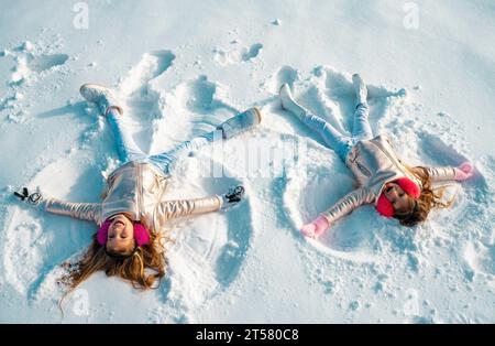 Due ragazze su un angelo di neve mostra. Bambini che giocano e fanno un angelo di neve nella neve. Vista dall'alto. Foto Stock