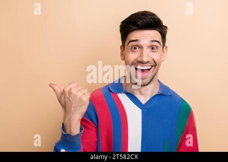 Ritratto di allegro uomo d'affari reazione sorpresa indicando dito vuoto spazio nuova proposta di offerta isolato su sfondo colore beige Foto Stock