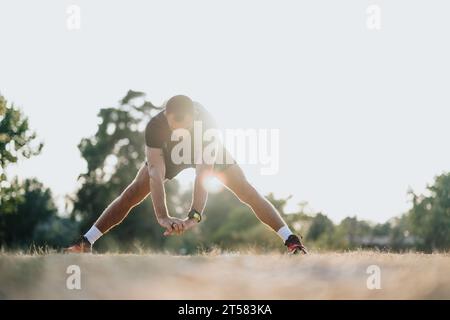 Attraente uomo nel parco che svolge sport all'aperto e stretching. Foto Stock