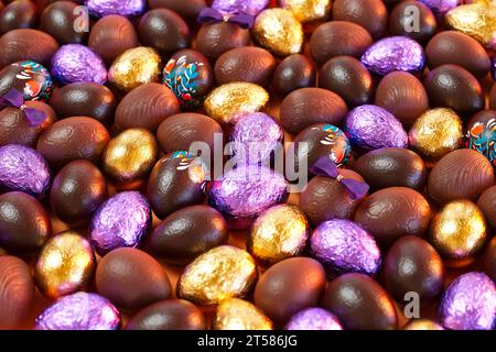 Raccolta di latte e uova di Pasqua al cioccolato fondente. Ogni uovo è decorato in modo unico, con alcuni avvolti in oro lucido e lamina viola - una t perfetta Foto Stock