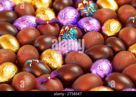 Raccolta di latte e uova di Pasqua al cioccolato fondente. Ogni uovo è decorato in modo unico, con alcuni avvolti in oro lucido e lamina viola - una t perfetta Foto Stock