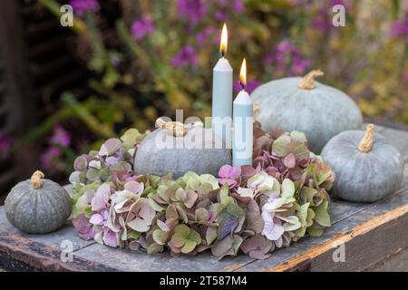 composizione autunnale con candele, corona di fiori di ortensia e zucche Foto Stock