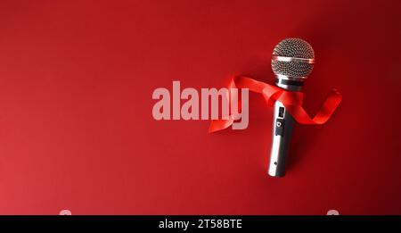 Microfono da palco metallico con arco rosso isolato su sfondo rosso. Vista dall'alto. Foto Stock