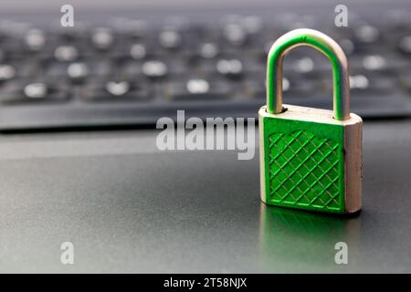 Lucchetto chiuso con luce verde che indica la sicurezza sullo sfondo della tastiera del computer Foto Stock
