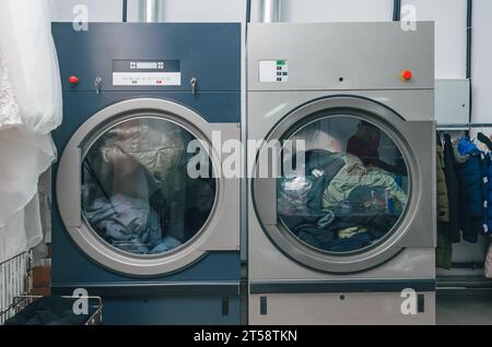 Vista frontale dell'asciugatrice per lavaggio a secco. I pulitori a secco sono dotati di due asciugatrici cariche di vestiti Foto Stock