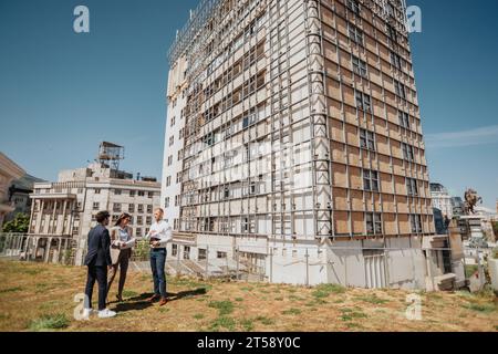 Team di tre architetti che discutono dei progressi della costruzione Foto Stock