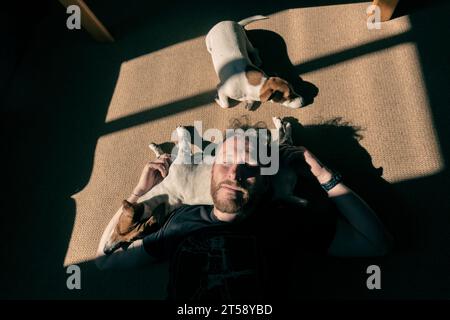 Un uomo si rilassa e si diverte con il suo cane Jack Russell alla luce del sole in una casa a Port Elizabeth in Sudafrica Foto Stock