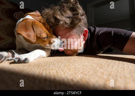 Un uomo si rilassa e si diverte con il suo cane Jack Russell alla luce del sole in una casa a Port Elizabeth in Sudafrica Foto Stock