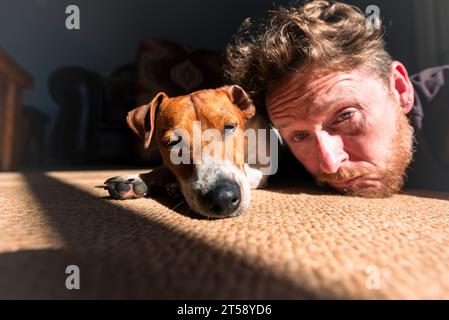 Un uomo si rilassa e si diverte con il suo cane Jack Russell alla luce del sole in una casa a Port Elizabeth in Sudafrica Foto Stock
