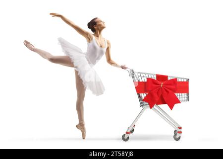 Foto a lunghezza intera di una ballerina con un abito tutu bianco che balla e tiene in mano un carrello con fiocco di nastro rosso isolato su sfondo bianco Foto Stock