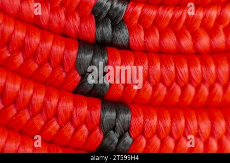 Consistenza di una corda elastica con gancio a spirale, in rosso e nero. Immagine macro. Contesto. Foto Stock