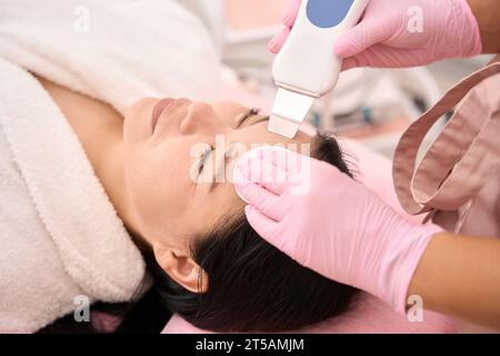 Signora asiatica sottoposta a pulizia del viso a ultrasuoni in un salone di bellezza Foto Stock