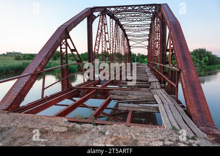 Vecchio ponte di ferro arrugginito sul fiume Foto Stock